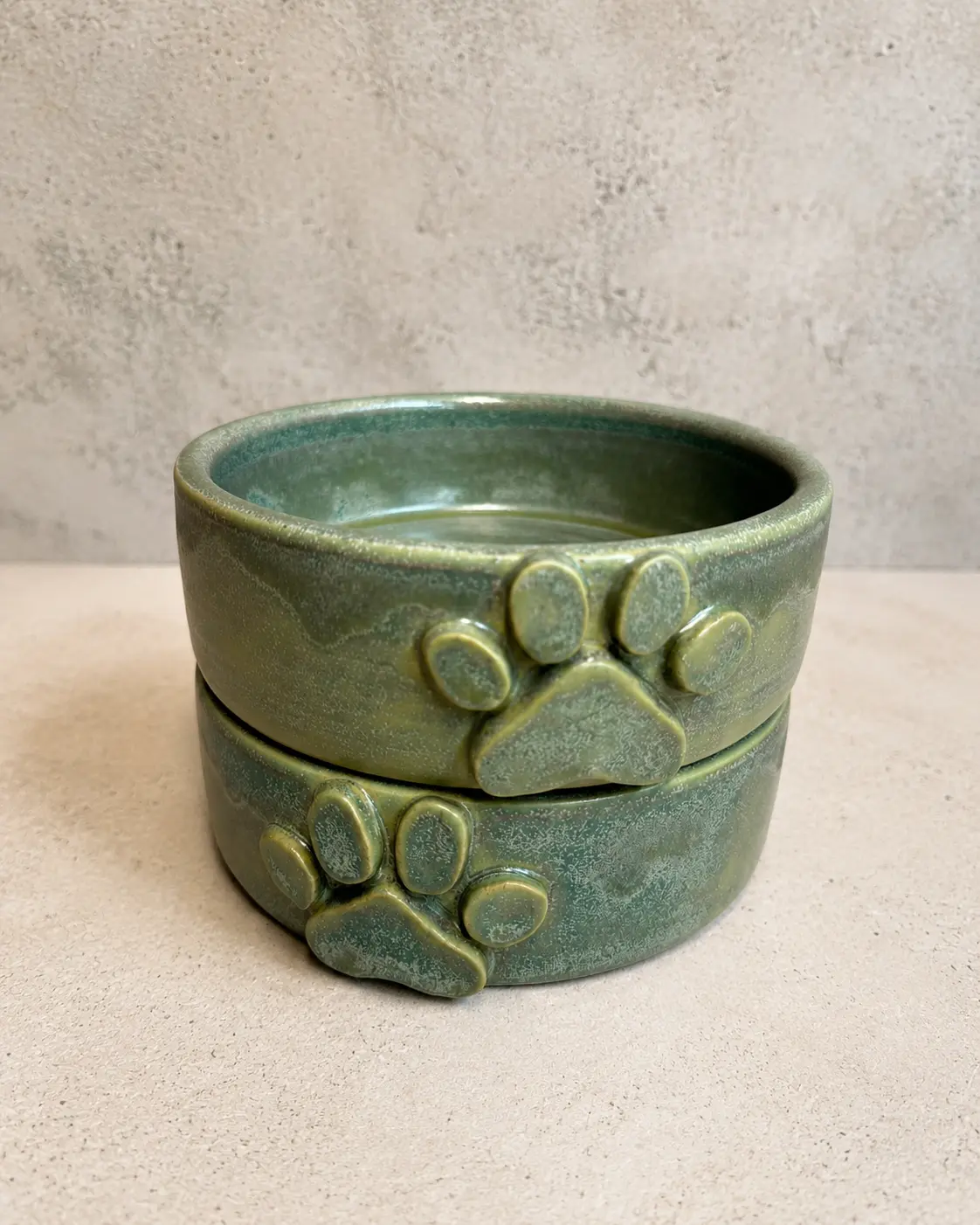 Two stacked green pet bowls with sculpted paw prints