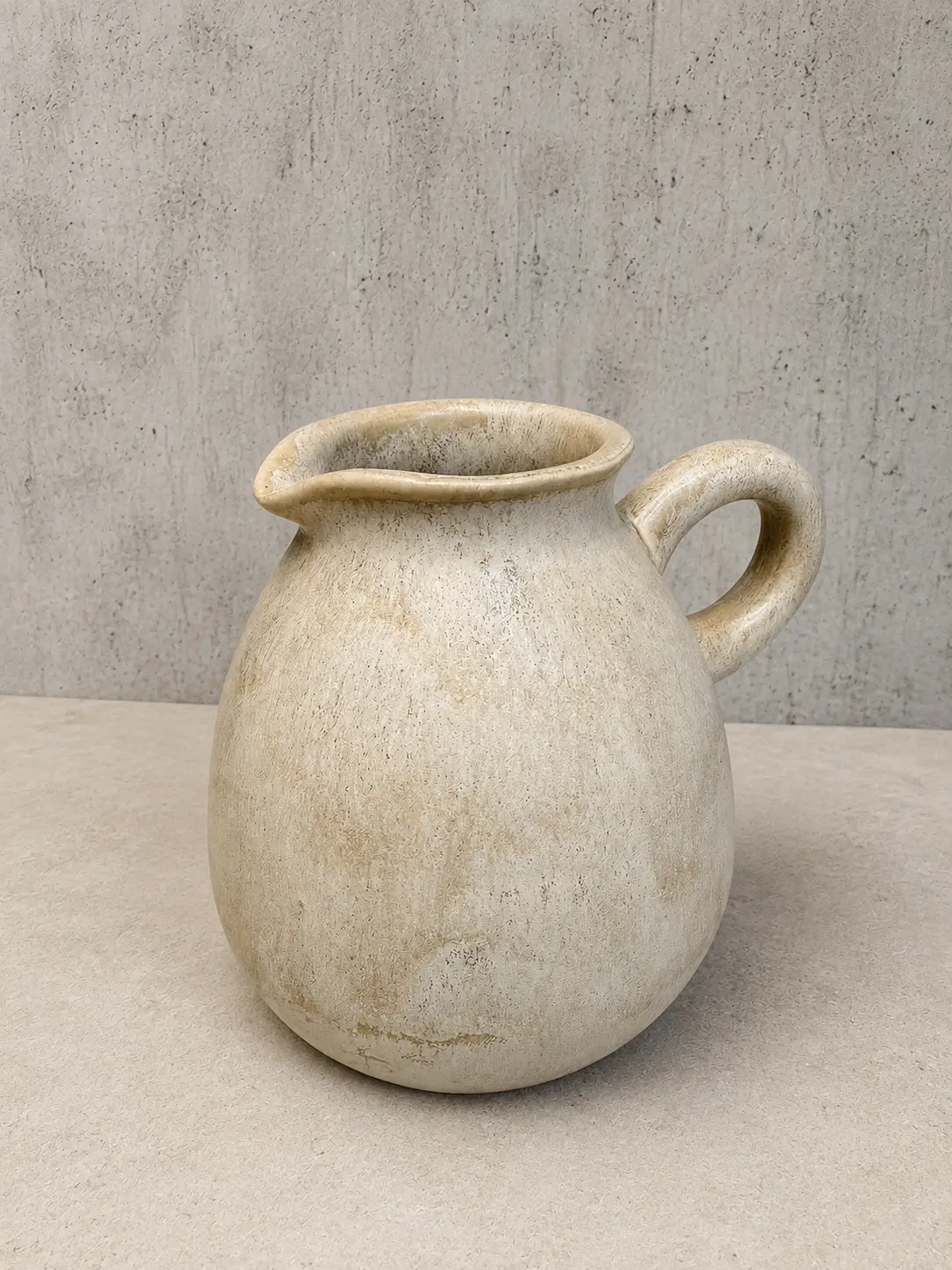 Sand-colored hand-thrown pitcher with a rolled handle