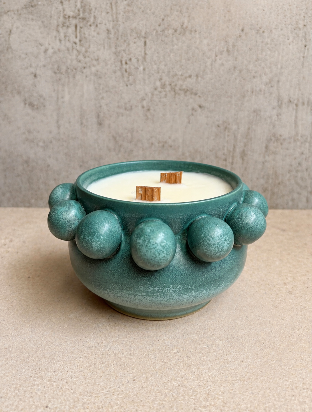 Teal bobble-textured ceramic vessel poured as a wood-wick candle