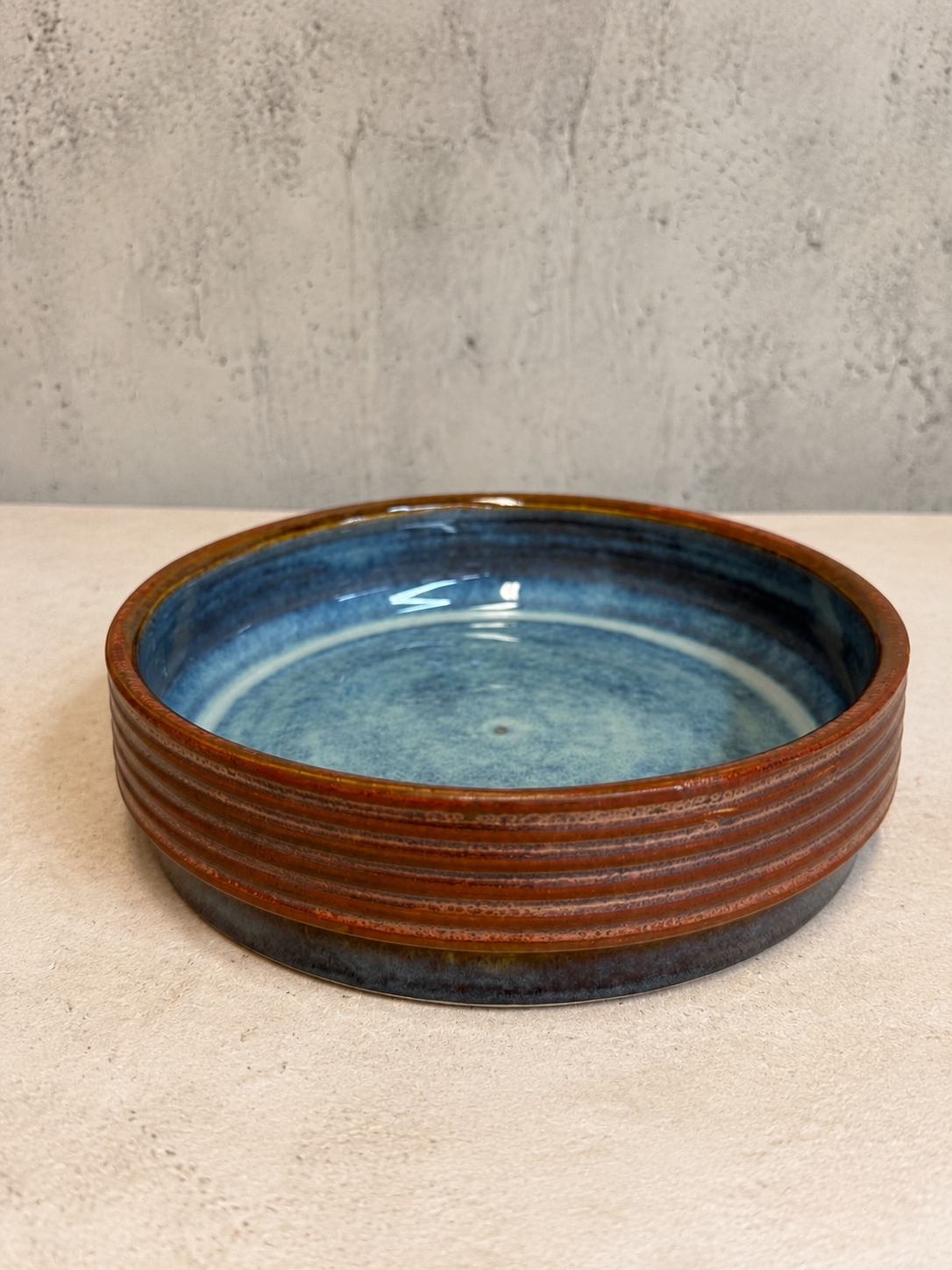 Shallow serving dish with rust ribbed exterior and deep blue interior